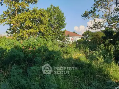 Lush greenery surrounds a distant house with a red roof, offering serene natural views.