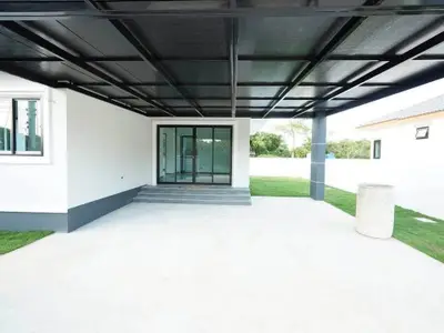 Modern house exterior with covered patio and glass doors, showcasing sleek design and spacious outdoor area.