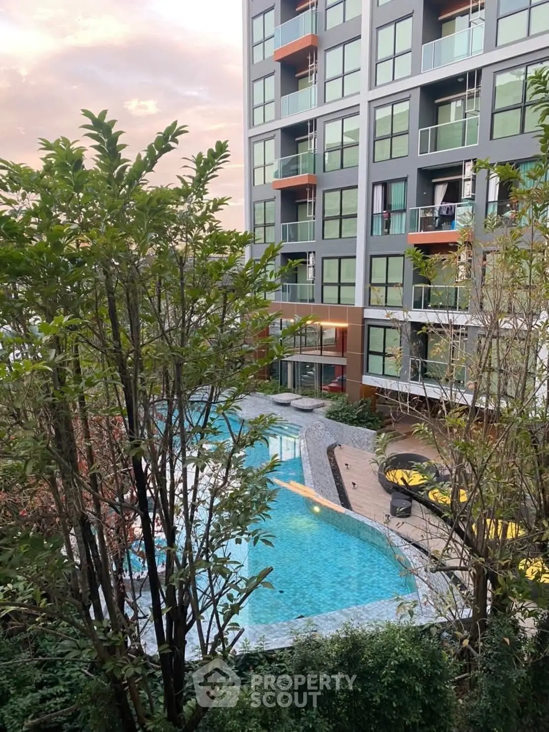 Modern apartment building with pool view and lush greenery, perfect for urban living.
