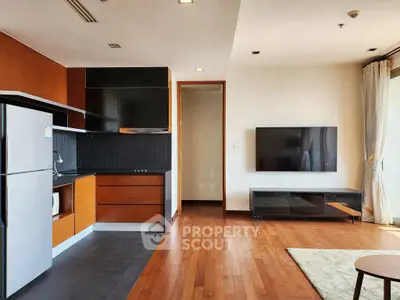 Modern open-layout living room with sleek kitchen and large wall-mounted TV