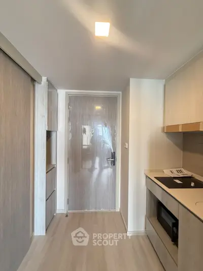 Modern apartment entrance with sleek kitchen and storage space