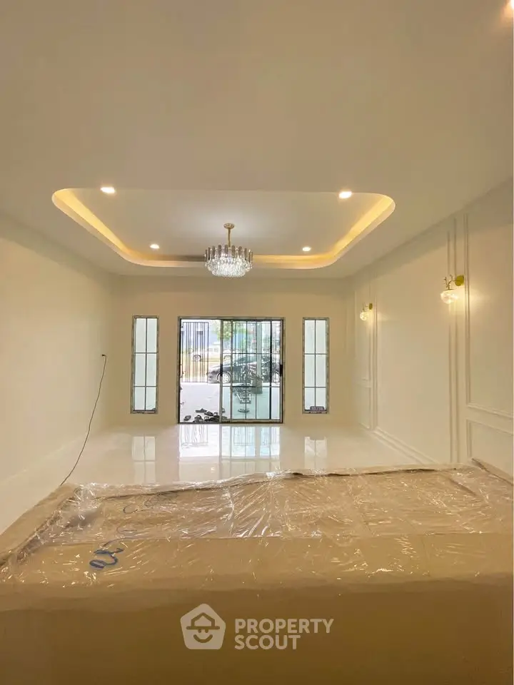 Spacious living room with elegant chandelier and large windows for natural light.