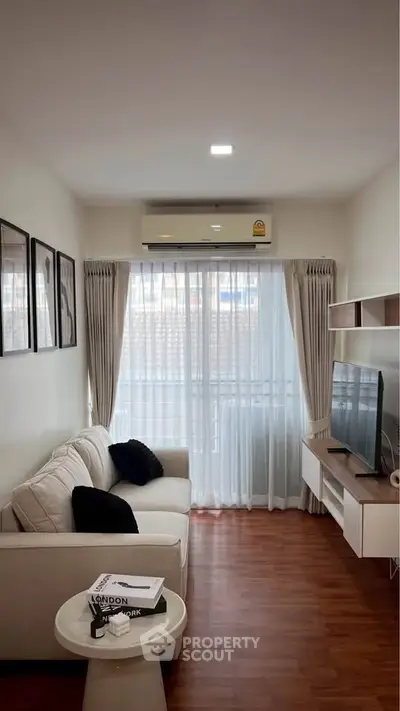 Cozy living room with modern decor and natural light, featuring a comfortable sofa and wall-mounted TV.
