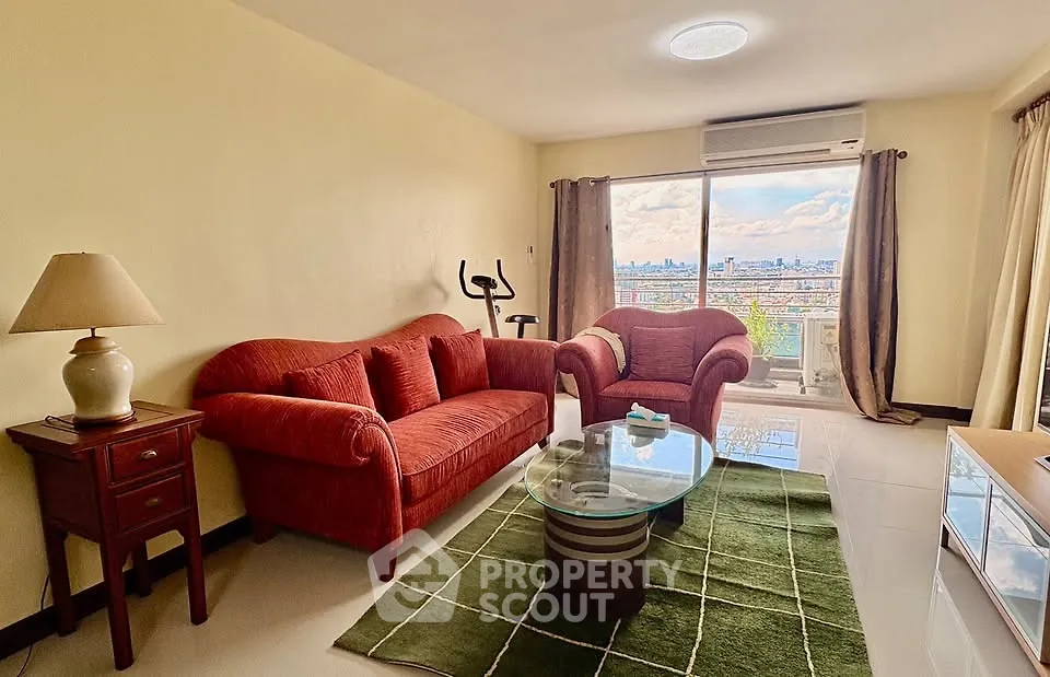 Spacious living room with city view, featuring cozy red sofa set and modern decor.