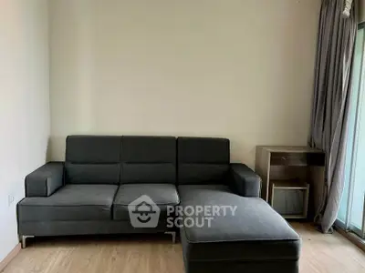 Modern living room with sleek gray sectional sofa and wooden flooring, perfect for cozy relaxation.