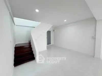 Spacious modern living room with sleek staircase and bright lighting, perfect for contemporary living.