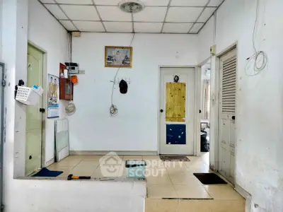 Spacious interior with tiled flooring and multiple doors, ideal for versatile use in a residential or commercial setting.