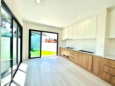 Bright modern kitchen with open layout and large windows overlooking garden.