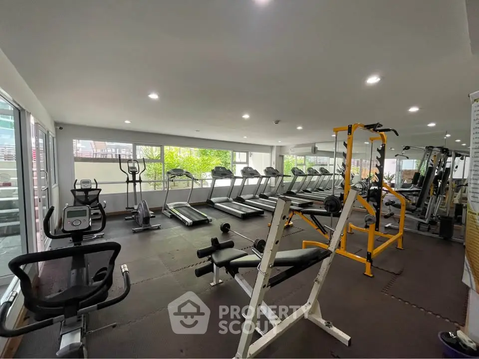 Spacious modern gym with state-of-the-art fitness equipment and large windows for natural light.