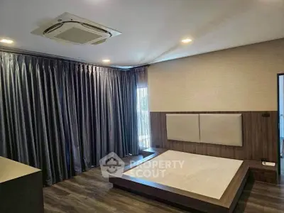 Spacious modern bedroom with elegant wood flooring and large windows.