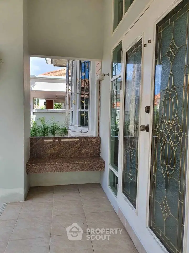 Charming entrance with elegant glass doors and tiled flooring in a serene residential setting.