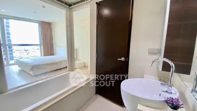 Modern bathroom with bathtub and view into a bright bedroom in a stylish apartment.
