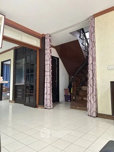 Spacious interior with tiled flooring and wooden staircase, ideal for family living.