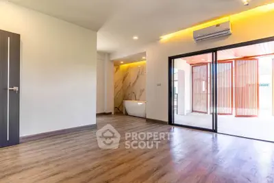 Spacious modern living room with wooden flooring and large sliding glass doors leading to a balcony.