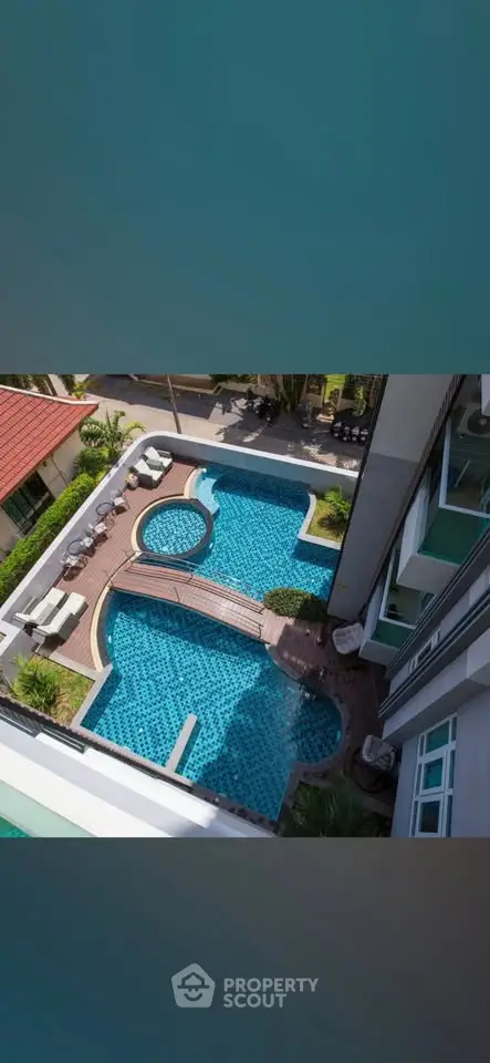 Luxurious apartment complex with stunning pool view from above, showcasing modern design and relaxation areas.