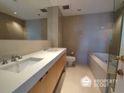 Spacious modern bathroom with dual vanity sinks, large mirror, and glass-enclosed shower, offering a luxurious and serene retreat.