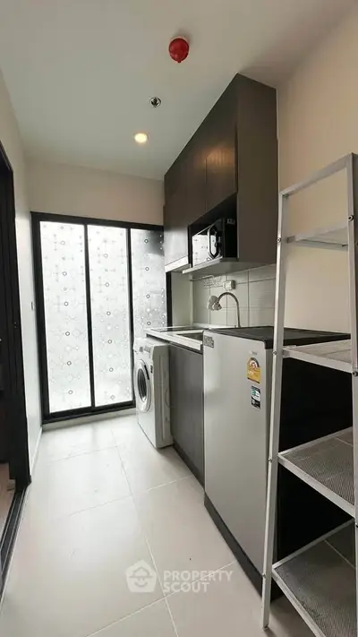 Modern kitchen with washing machine and fridge in sleek apartment