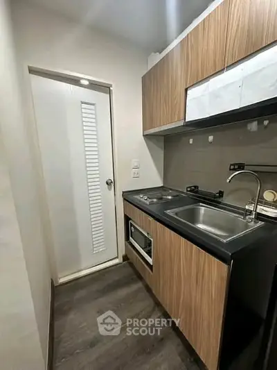 Modern compact kitchen with sleek wooden cabinets and stainless steel appliances