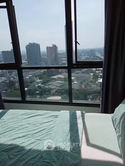 Stunning city view from a high-rise bedroom window, showcasing urban skyline and natural light.