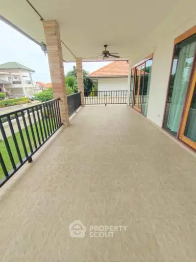 Spacious balcony with elegant railing and ceiling fan overlooking lush greenery.