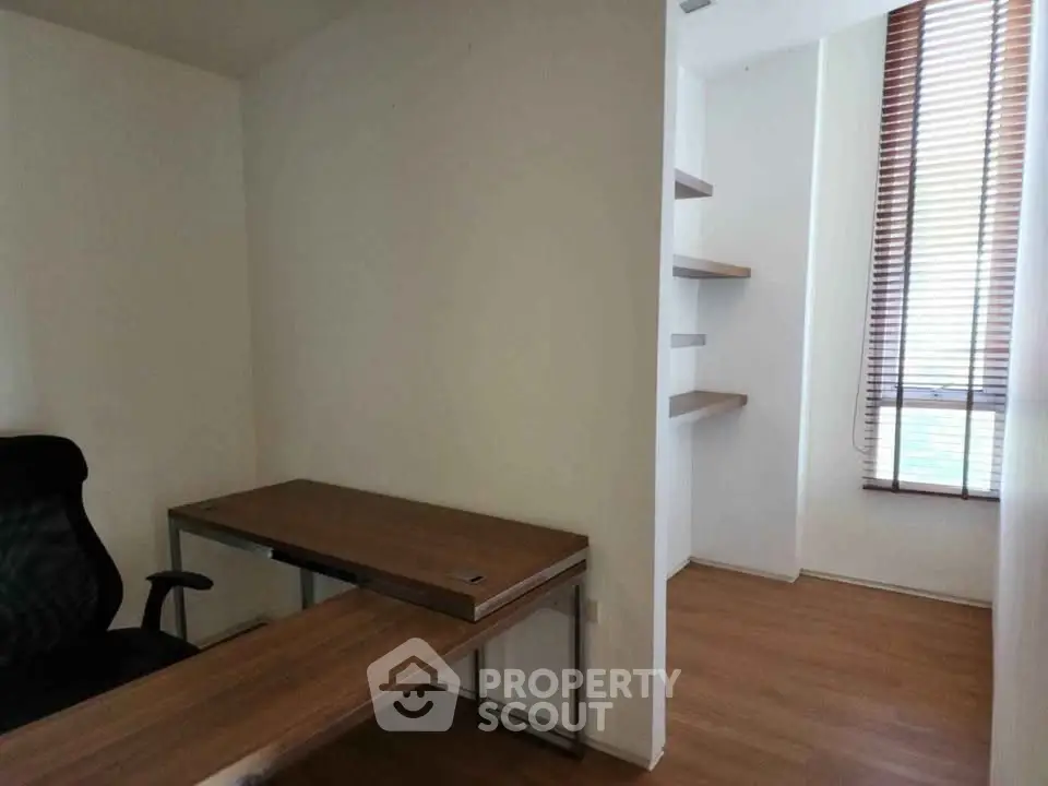 Modern study room with wooden desk and shelves, featuring natural light from large window.