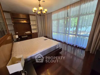 Spacious bedroom with large windows and elegant wooden flooring