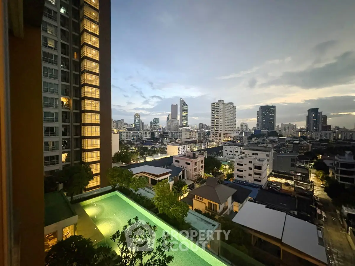 Stunning cityscape view from high-rise apartment with illuminated pool at dusk.
