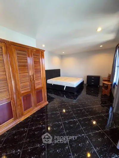 Spacious bedroom with elegant wooden wardrobe and sleek black tile flooring