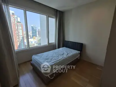 Cozy bedroom with city view, featuring a single bed and large windows for natural light.