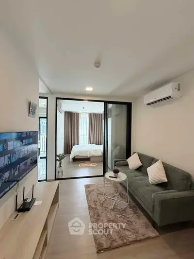 Modern living room with cozy sofa, TV, and view into stylish bedroom