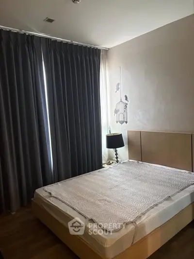 Cozy bedroom with modern decor and large window with dark curtains.