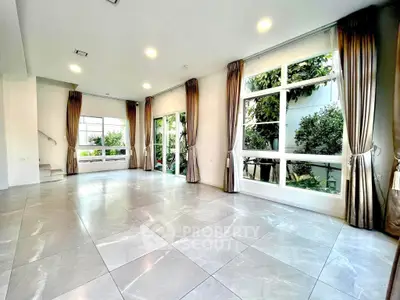 Spacious modern living room with large windows and garden view, perfect for family gatherings.