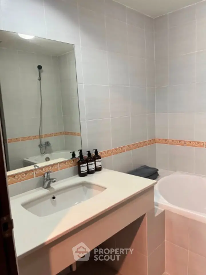Modern bathroom with sleek sink and bathtub, featuring elegant tile design and stylish fixtures.