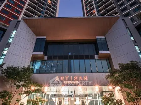 Modern high-rise building entrance with sleek design and illuminated signage.