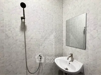 Modern minimalist bathroom with sleek shower and elegant sink in a stylish tiled setting.