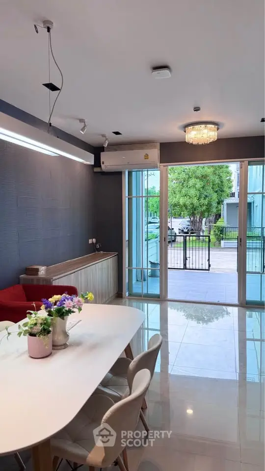 Modern living room with elegant dining area and large glass doors opening to a lush garden view.