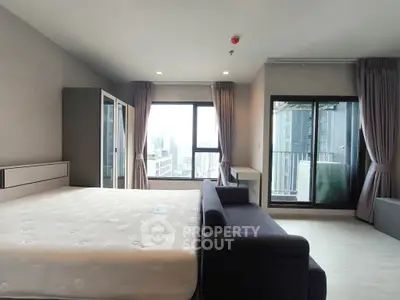 Spacious bedroom with city view and balcony access in modern apartment