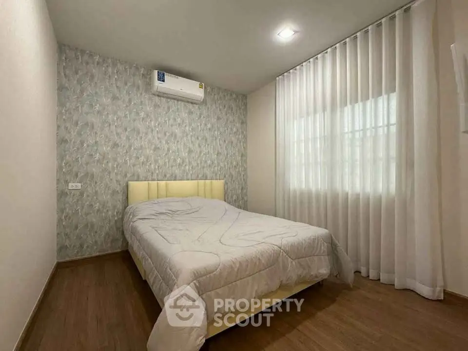 Cozy bedroom with modern decor and natural light, featuring a comfortable bed and stylish wallpaper.