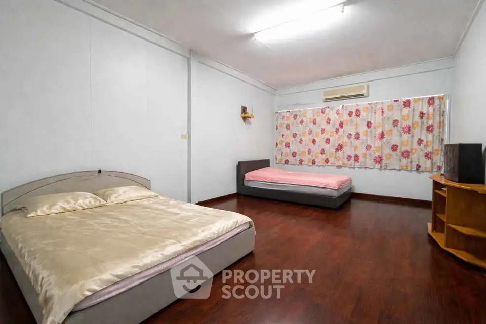 Spacious bedroom with two beds and wooden flooring, ideal for comfortable living.