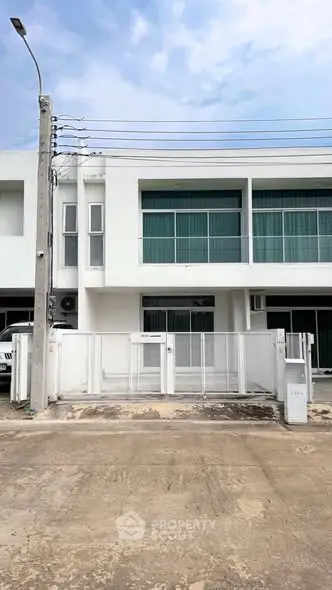 Modern white townhouse exterior with large windows and gated entrance