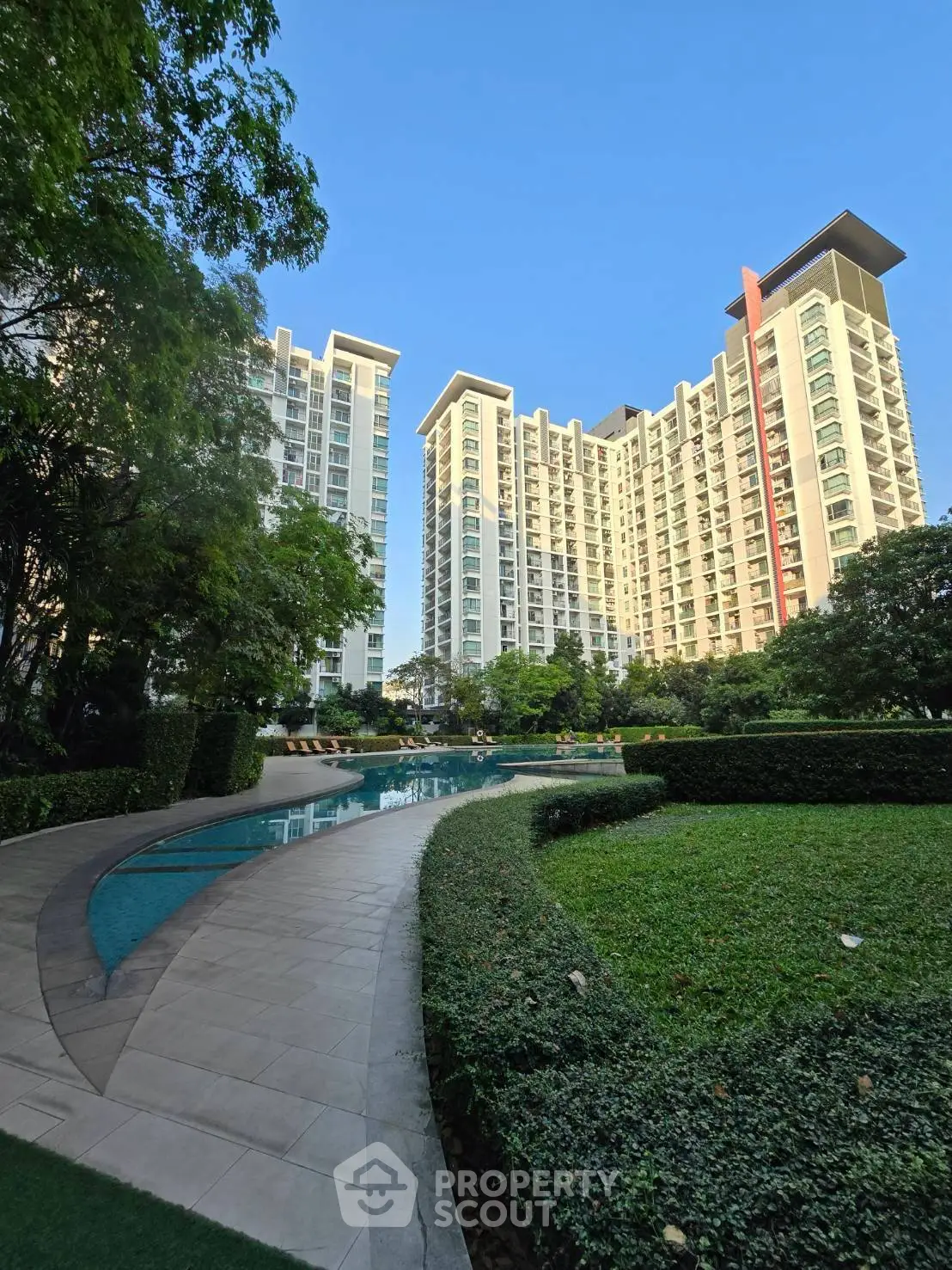 Luxurious high-rise residential buildings with lush gardens and a serene pool area.