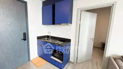 Compact modern kitchen with blue cabinets and built-in microwave