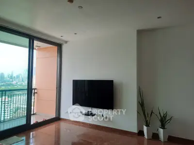 Spacious living room with modern TV setup and balcony view of city skyline.