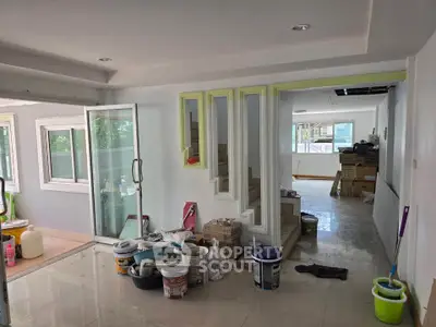 Spacious interior under renovation with modern glass door and ample natural light.