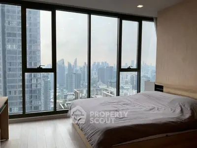 Luxurious bedroom with floor-to-ceiling windows offering stunning city skyline views.