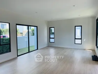 Spacious empty room with large windows and wooden flooring, ideal for customization.