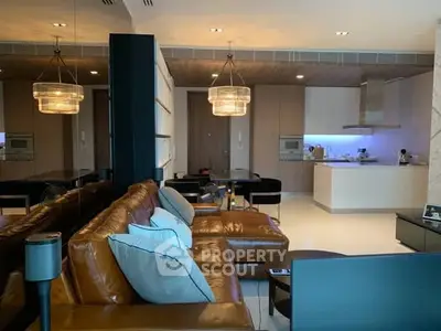 Luxurious modern living room with open kitchen, leather sofa, and elegant lighting.