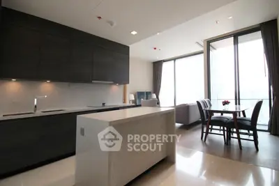 Modern open-layout kitchen and living area with large windows and elegant dining space.