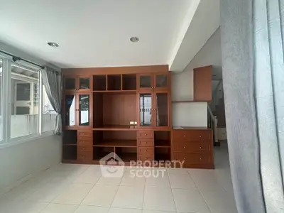 Spacious living room with built-in wooden shelving and large windows for natural light.