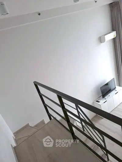 Modern loft-style living room with sleek staircase and minimalist decor